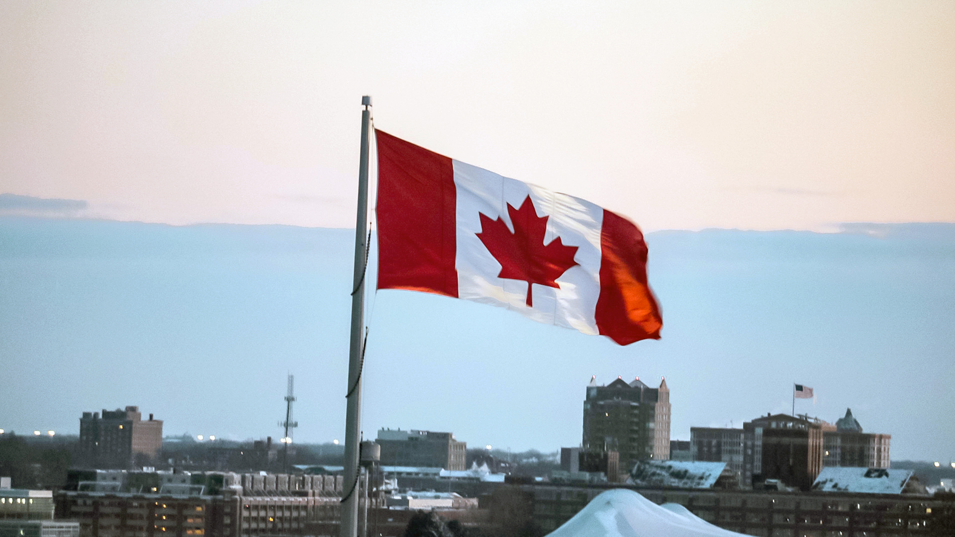 A Canadian flag flying atop city buildings